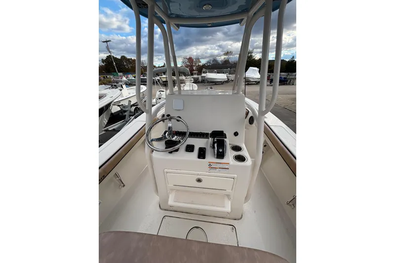 Slide: The Image of 2023 Sea Chaser 24 HFC boat console with steering wheel and controls, under a cloudy sky. - 9