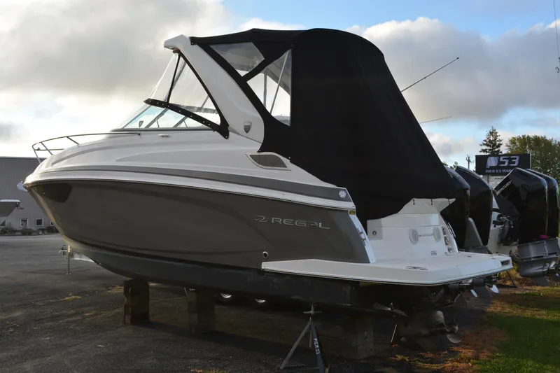 Slide: The Image of 2016 Regal 28 Express boat with black canopy, parked on a lot. - 2