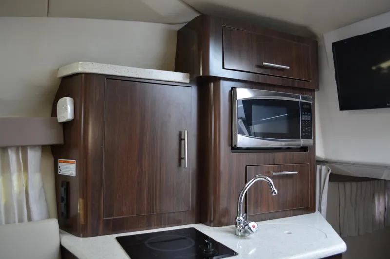 Slide: The Image of 2016 Regal 28 Express interior kitchen with microwave, sink, and wooden cabinetry. - 21
