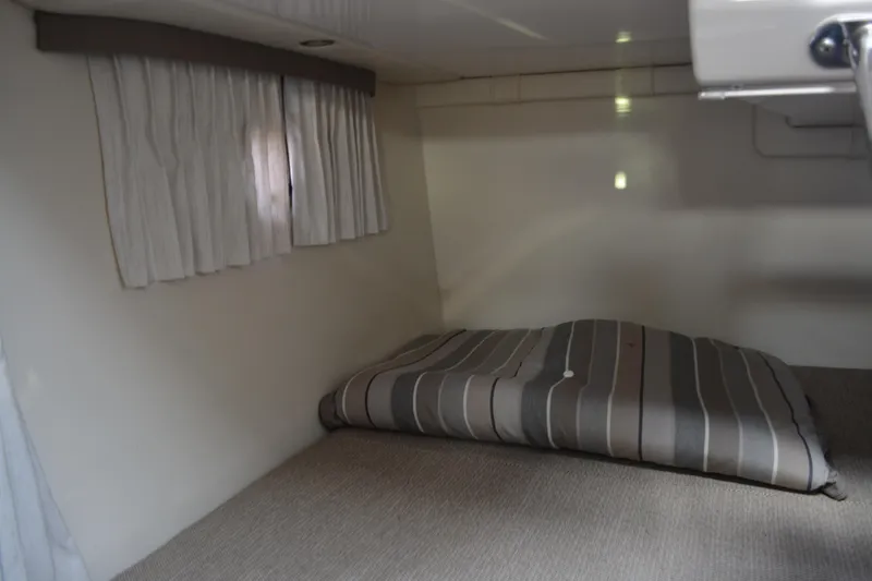 Slide: The Image of 2016 Regal 28 Express cabin interior with striped bedding and curtains. - 24