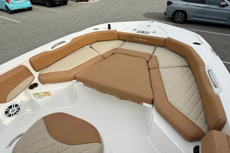 Slide: The Image of 2025 NauticStar 191 Hybrid boat with tan and beige cushioned seating in a parking lot. - 13