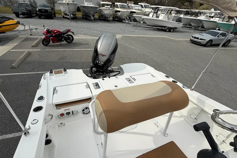 Slide: The Image of 2025 NauticStar 191 Hybrid boat interior with motor, parked near motorcycles and cars. - 19
