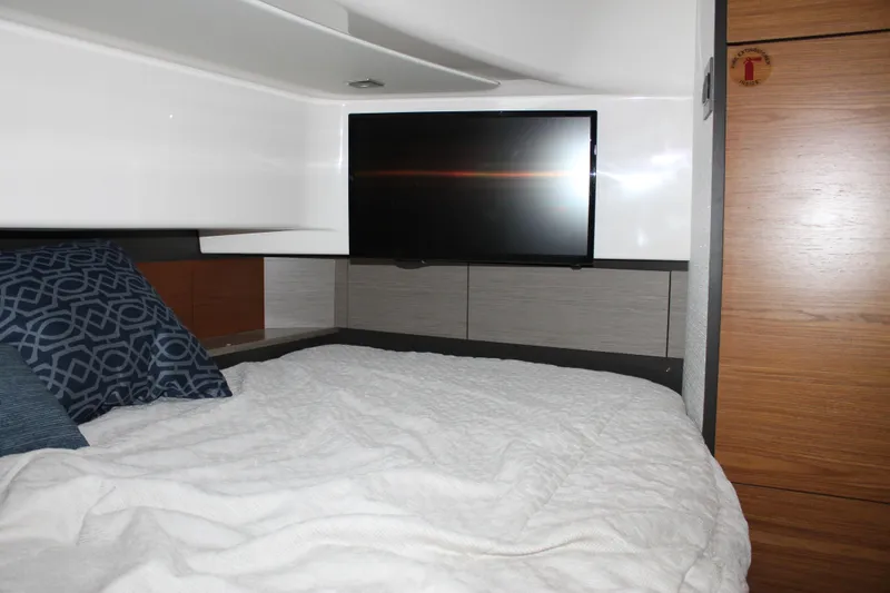 Slide: The Image of 2022 Tiara Yachts 43 LS cabin interior with bed, pillows, and wall-mounted TV. - 30