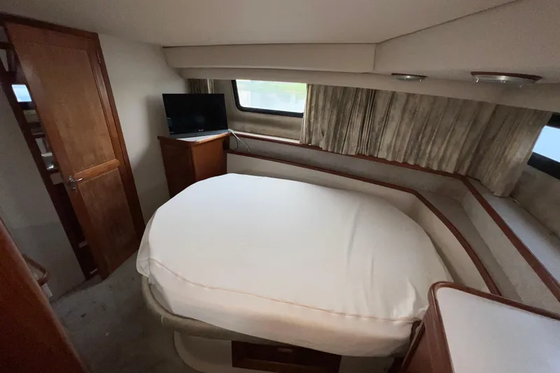 Slide: The Image of 1988 Carver 3807 Aft Cabin Motor Yacht bedroom with bed, TV, and window. - 10