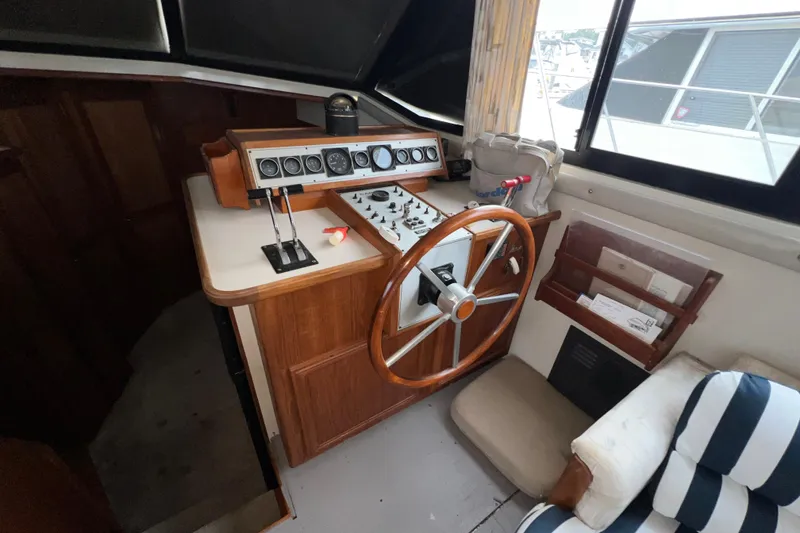 Slide: The Image of 1988 Carver 3807 Aft Cabin Motor Yacht helm with wooden steering wheel and control panel. - 13