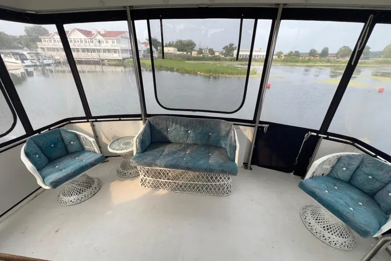 Slide: The Image of 1988 Carver 3807 Aft Cabin Motor Yacht interior with blue cushioned seating and waterfront view. - 6