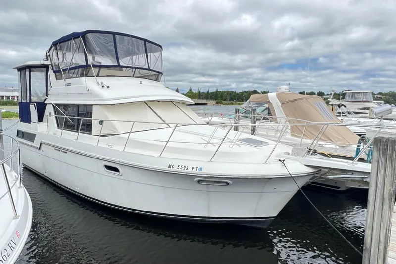 The Image of 1988 Carver 3807 Aft Cabin Motor Yacht docked at marina under cloudy sky. - 1