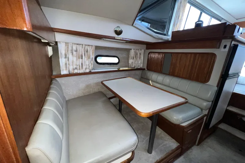Slide: The Image of 1988 Carver 3807 Aft Cabin Motor Yacht interior dining area with cushioned seating and table. - 15