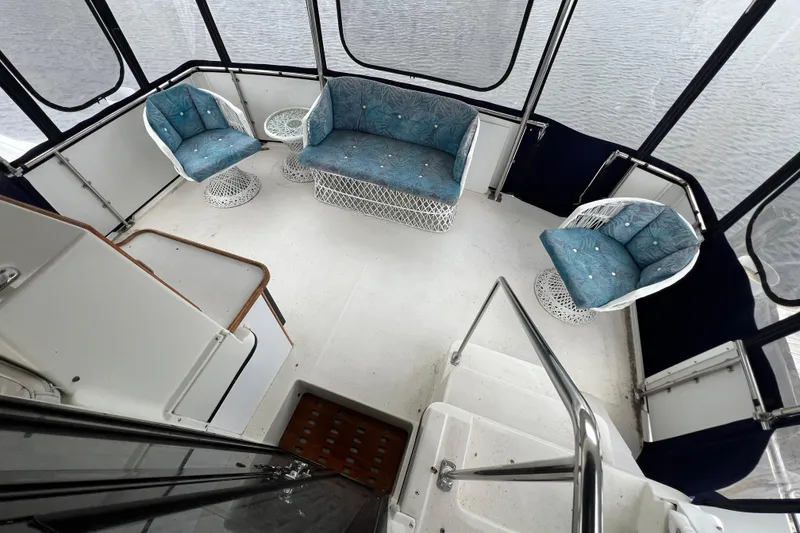 Slide: The Image of 1988 Carver 3807 Aft Cabin Motor Yacht interior with blue cushioned seating and white wicker furniture. - 23
