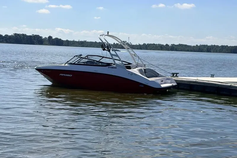 Slide: The Image of 2024 Yamaha AR190 boat docked on a serene lake under a clear sky. - 2