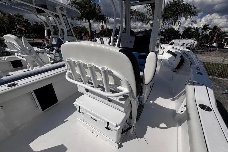 Slide: The Image of 2026 Tidewater 232 CC Adventure boat interior with rod holders and seating under a cloudy sky. - 13