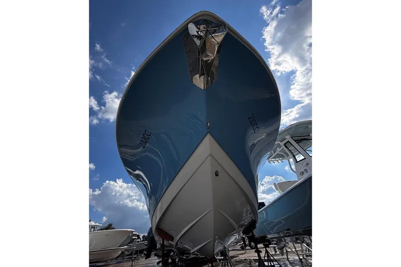 Slide: The Image of 2026 Tidewater 232 CC Adventure boat, blue hull, viewed from below against a cloudy sky. - 2