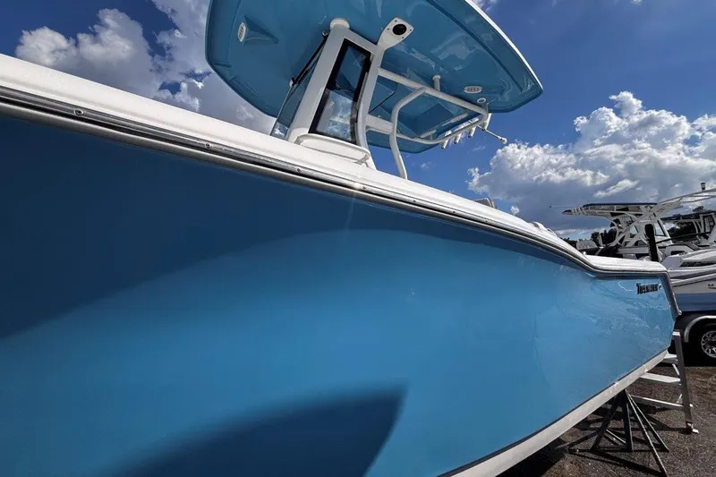 Slide: The Image of 2026 Tidewater 232 CC Adventure boat with blue hull under a cloudy sky. - 4