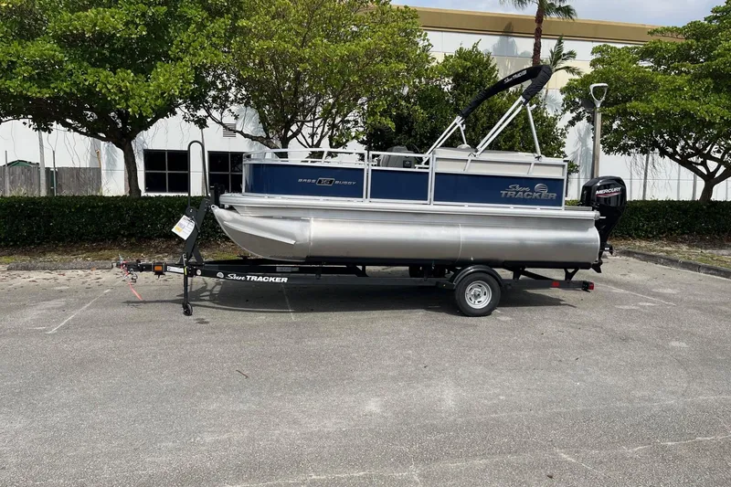 The Image of 2026 Sun Tracker Bass Buggy 16 XL Select pontoon boat on trailer in parking lot. - 0