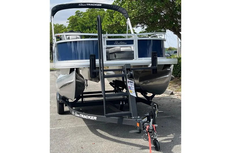 Slide: The Image of 2026 Sun Tracker Bass Buggy 16 XL Select pontoon boat on trailer, parked outdoors. - 4