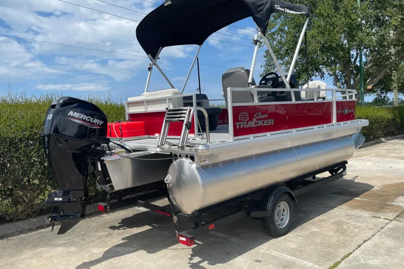 Slide: The Image of 2026 Sun Tracker Bass Buggy 16 XL Select pontoon boat with Mercury engine, parked outdoors. - 4