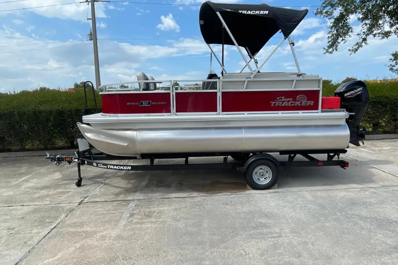 The Image of 2026 Sun Tracker Bass Buggy 16 XL Select pontoon boat on trailer, outdoor setting. - 0