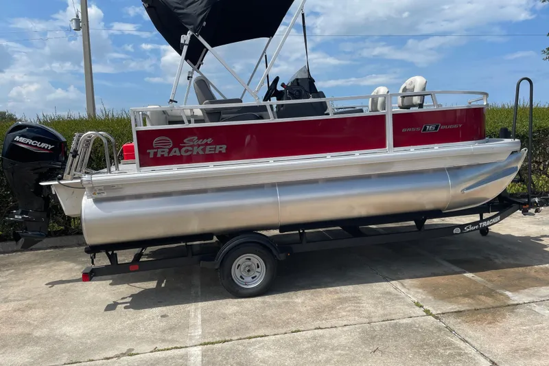 Slide: The Image of 2026 Sun Tracker Bass Buggy 16 XL Select pontoon boat on trailer, featuring Mercury outboard motor. - 3
