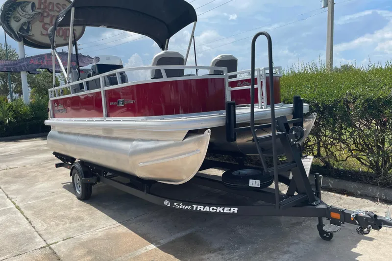 Slide: The Image of 2026 Sun Tracker Bass Buggy 16 XL Select pontoon boat on trailer, parked outdoors. - 5