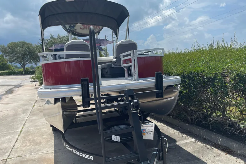 Slide: The Image of 2026 Sun Tracker Bass Buggy 16 XL Select pontoon boat on trailer, parked outdoors. - 14