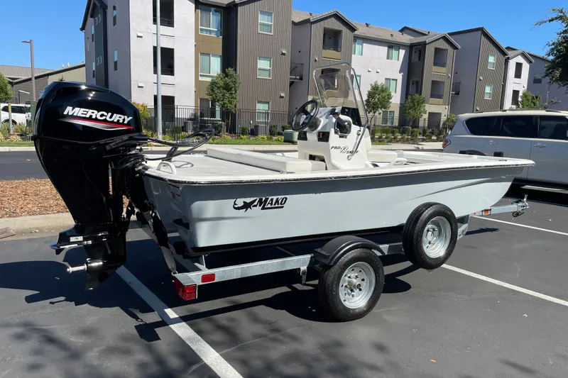 Slide: The Image of 2026 Mako Pro Skiff 13 CC boat on trailer, parked in urban setting. - 3