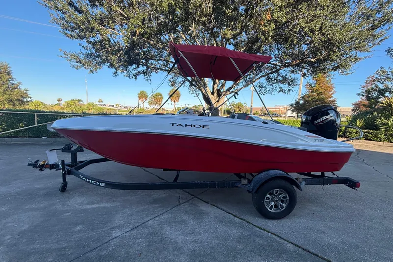 The Image of 2026 Tahoe T18 boat with red hull and canopy on a trailer. - 0