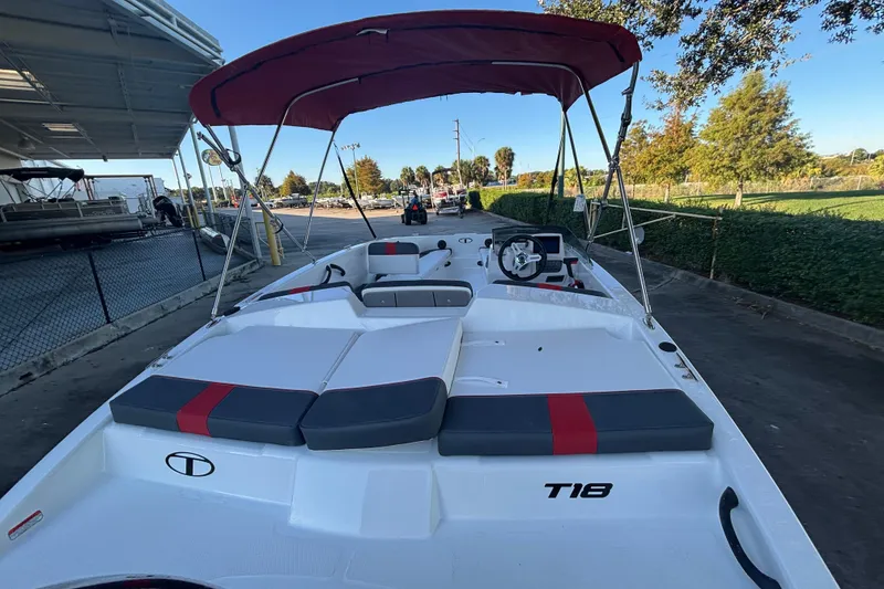 Slide: The Image of 2026 Tahoe T18 boat with red canopy, docked outdoors on a sunny day. - 1