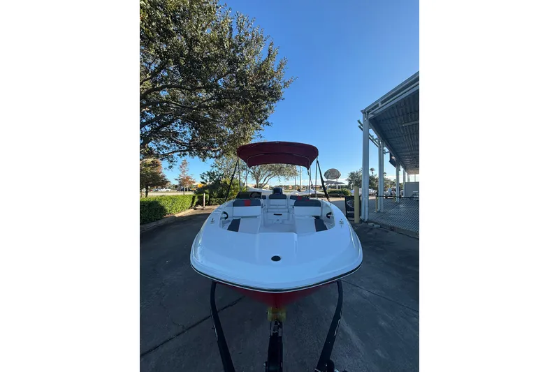 Slide: The Image of 2026 Tahoe T18 boat with red canopy, parked outdoors under clear blue sky. - 2