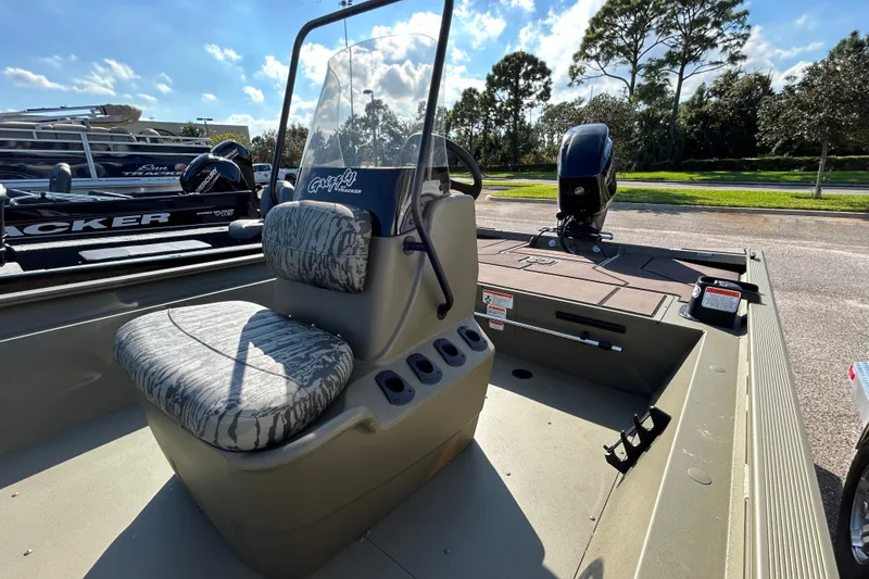 Slide: The Image of 2026 Tracker Grizzly 1860 CC boat interior with seating and console, parked outdoors. - 4
