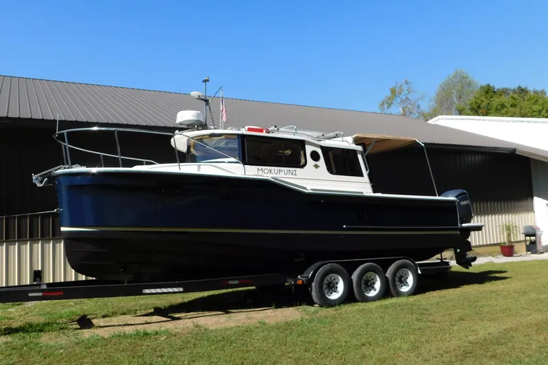 Slide: The Image of 2022 Ranger Tugs R-27 boat on trailer, parked outdoors near a building. - 18