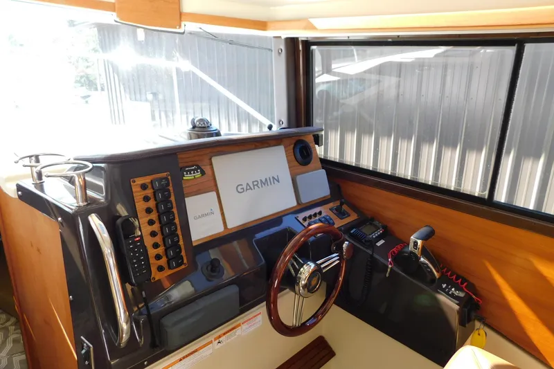 Slide: The Image of 2022 Ranger Tugs R-27 helm with Garmin navigation system and wooden steering wheel. - 34