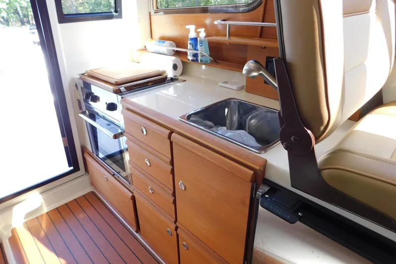 Slide: The Image of 2022 Ranger Tugs R-27 interior kitchen with wooden cabinetry and compact sink. - 40