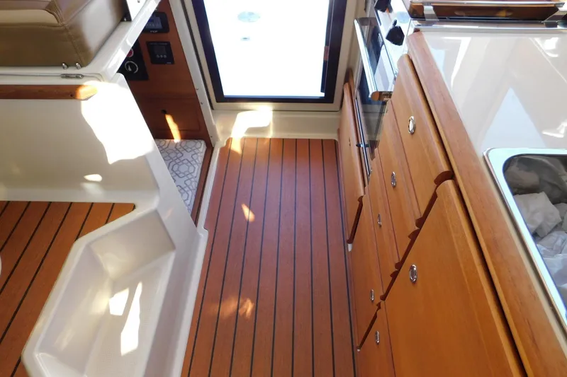 Slide: The Image of 2022 Ranger Tugs R-27 interior with wood flooring and cabinetry, showcasing a compact kitchen area. - 41