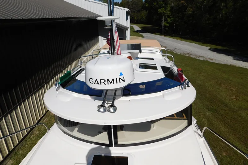 Slide: The Image of 2022 Ranger Tugs R-27 boat with Garmin radar, docked near a grassy area. - 47