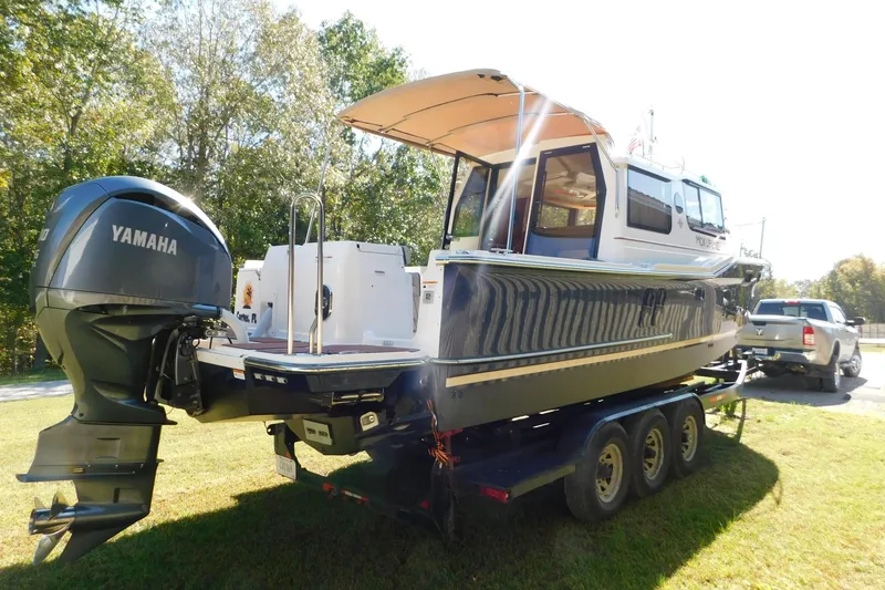 Slide: The Image of 2022 Ranger Tugs R-27 boat on trailer with Yamaha outboard motor, parked on grass. - 51