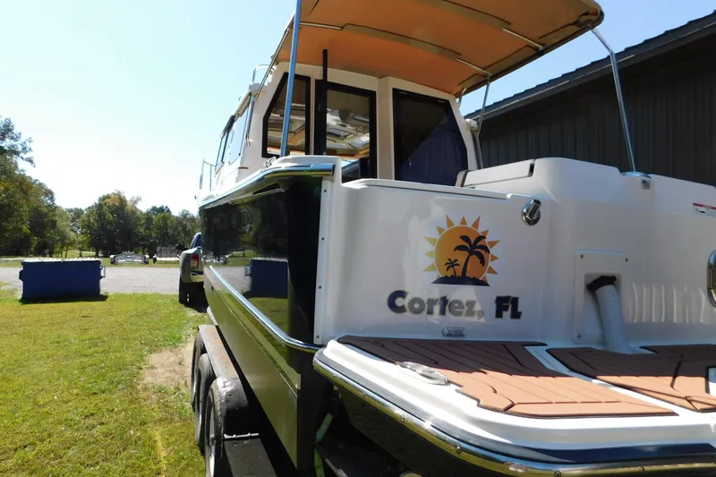 Slide: The Image of 2022 Ranger Tugs R-27 boat with Cortez, FL logo, parked on grass. - 56