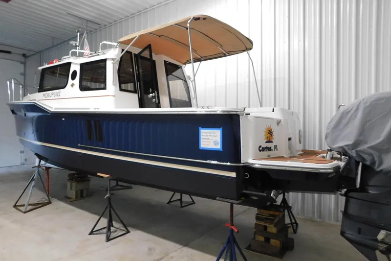 Slide: The Image of 2022 Ranger Tugs R-27 boat in storage, blue hull, tan canopy, located in Cortez, FL. - 6