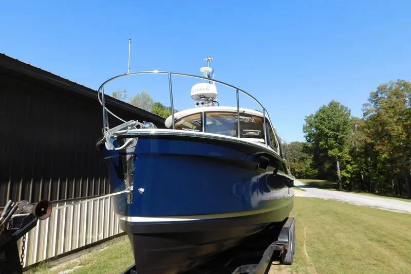 Slide: The Image of 2022 Ranger Tugs R-27 boat on trailer, parked outdoors under clear blue sky. - 61