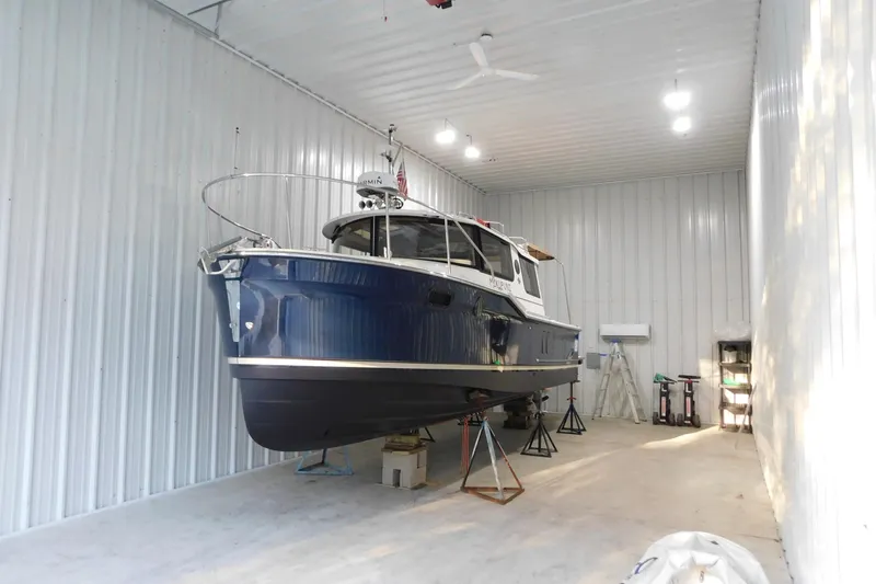 Slide: The Image of 2022 Ranger Tugs R-27 boat in storage, blue hull, indoor facility. - 64