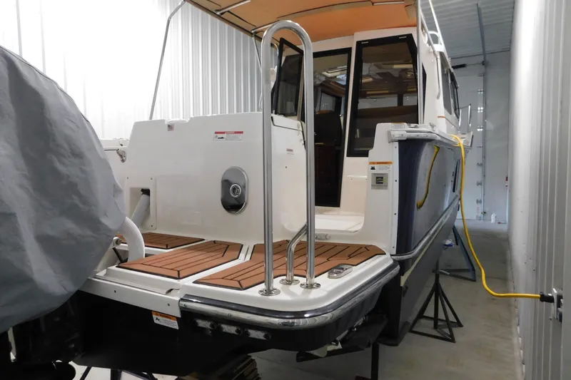 Slide: The Image of 2022 Ranger Tugs R-27 boat in storage, showcasing rear deck and stainless steel railings. - 66