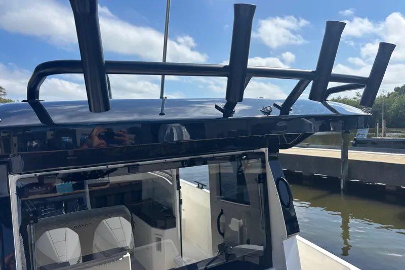 Slide: The Image of 2026 Navan C30 boat with rod holders, docked by the water under a clear sky. - 13