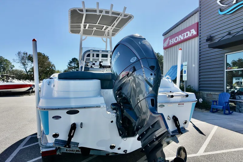 Slide: The Image of 2025 NauticStar 212 Legacy boat with Yamaha engine, parked near a Honda dealership. - 7