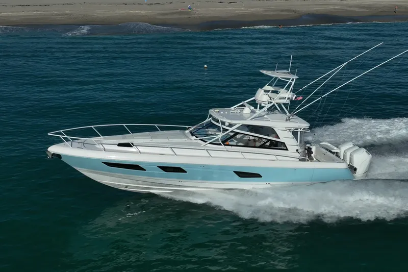 The Image of 2023 Intrepid 477 Evolution yacht cruising on ocean near sandy beach. - 0