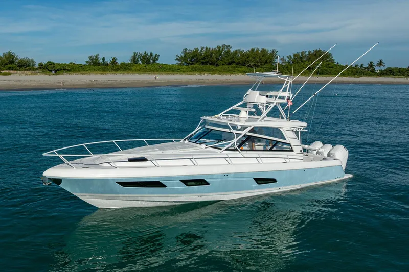 Slide: The Image of 2023 Intrepid 477 Evolution yacht cruising near a sandy shoreline. - 10