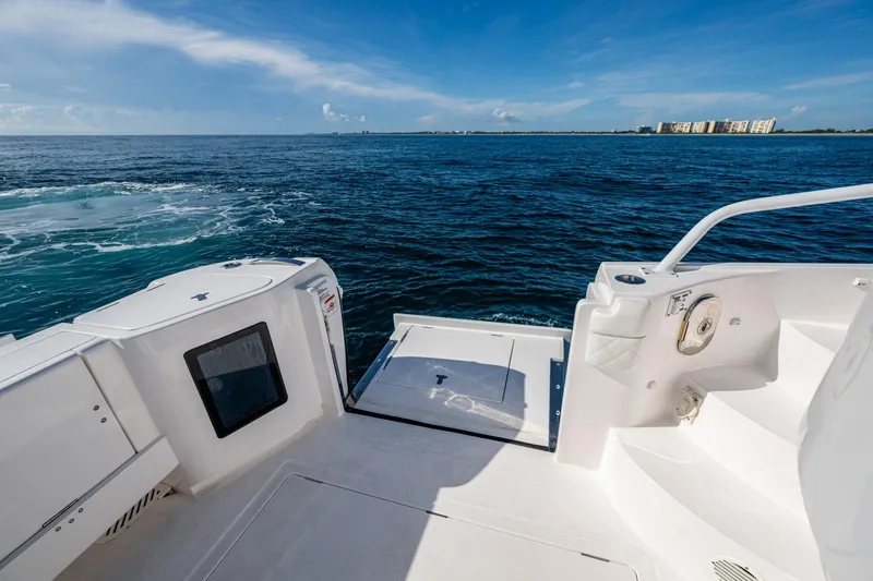 Slide: The Image of Sleek 2023 Intrepid 477 Evolution yacht deck overlooking the ocean under a clear blue sky. - 51