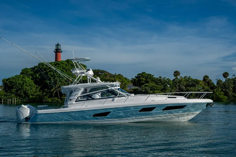 Slide: The Image of 2023 Intrepid 477 Evolution yacht cruising near a lighthouse and lush greenery. - 73