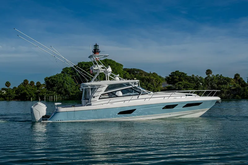 Slide: The Image of 2023 Intrepid 477 Evolution yacht cruising on a serene waterway with lush greenery. - 74