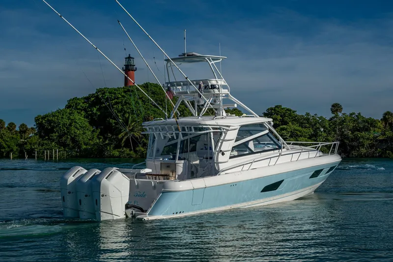 Slide: The Image of 2023 Intrepid 477 Evolution yacht cruising near a lighthouse, surrounded by lush greenery. - 76