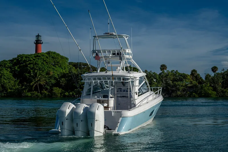 Slide: The Image of 2023 Intrepid 477 Evolution boat cruising near a lighthouse and lush greenery. - 78