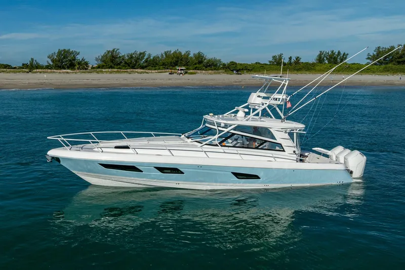 Slide: The Image of 2023 Intrepid 477 Evolution boat on calm blue water near a sandy beach. - 8